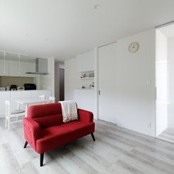 白を基調とした開放的なリビング。空間を引き締める赤いソファがアクセントのスタイリッシュなリビング